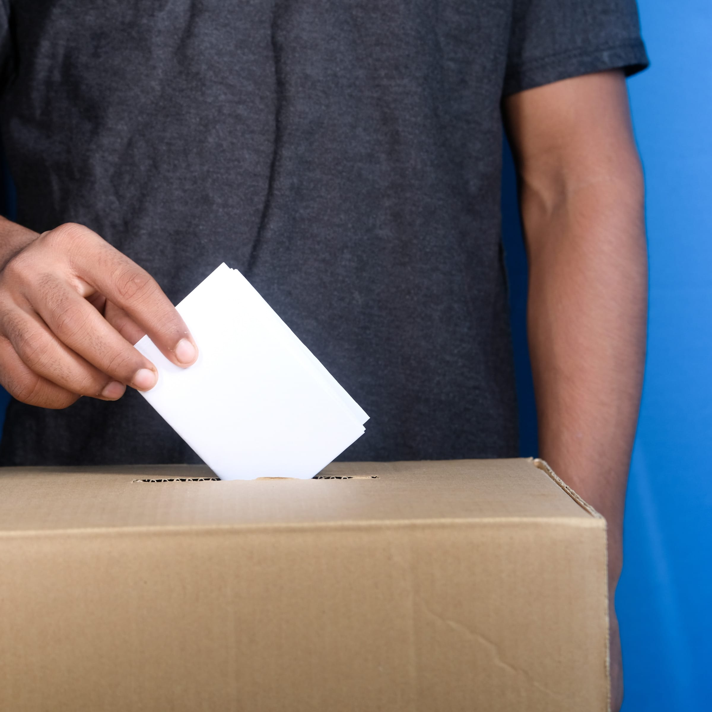 Man's hand putting a ballot into a ballot box
