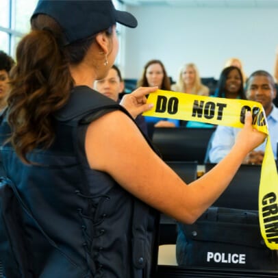 A female training instructor holding up caution tape to show a class